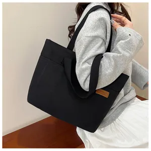 Sac cabas noir décontracté en toile pour le quotidien, grand sac porté épaule étudiant.