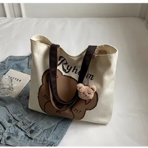 Canvas tote bag detail showcasing cute bear graphic print and brown shoulder straps.