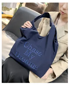 Detailed view of the dark blue nylon tote bag with stylish embroidered letter design.