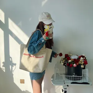 Detail shot of the casual canvas shoulder bag with red letter print in a stylish room setup.