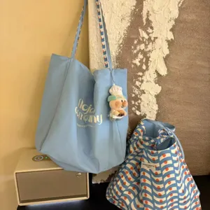 Casual canvas tote bag for women, large capacity shoulder bag with cute plush pendant and stylish design.