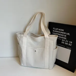 Canvas tote bag detail view, minimalist beige daily shoulder bag with front pocket.