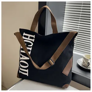 Vue détaillée du sac cabas en toile noire avec des lanières marron et une impression blanche.