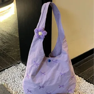 Lavender canvas shoulder bag with cute embroidered bows and knit flower charm for casual daily use.