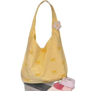 Yellow canvas shoulder tote bag with cute bow embroidery and flower pendant for daily commuting.