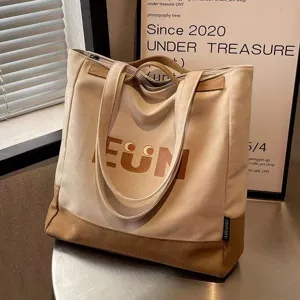 Canvas tote bag detail showing large capacity, dual straps and EUM letter print.