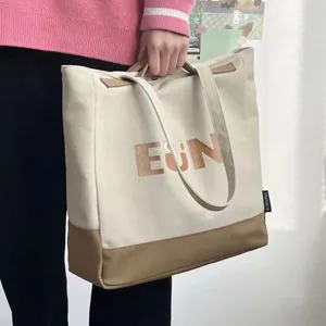 Close-up detail of the canvas tote bag showing the dual handles and front EUN letter print.