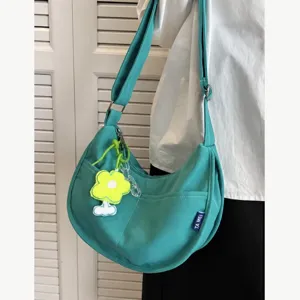 Casual crescent canvas shoulder bag for women, stylish crossbody bag with cute flower pendant.
