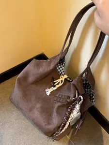 Brown suede tote bag close-up showing black and white check lining and cute charms.