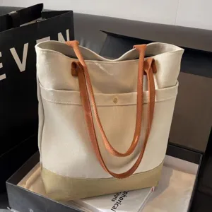 Canvas tote bag detail showing sturdy brown straps, front pocket, and spacious interior design.