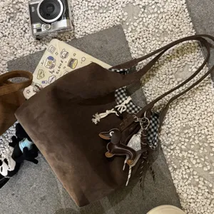 Brown suede shoulder tote bag detail view, featuring cute dachshund charm and checkered lining.