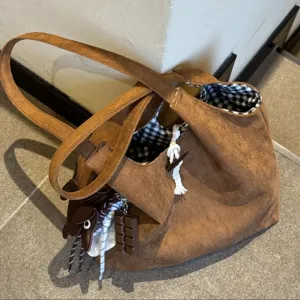 Brown suede shoulder tote bag featuring black and white checkered lining and charms.