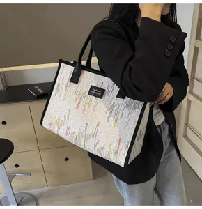 Detailed view of large capacity canvas tote shoulder bag with colorful embroidered abstract lines.