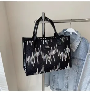 Detailed close-up view of large capacity black canvas tote bag with shiny embroidery.