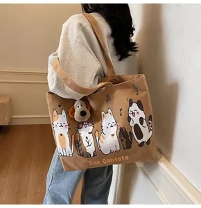 Detailed close-up of the casual brown canvas tote bag with cute cat prints and a plush dog pendant.
