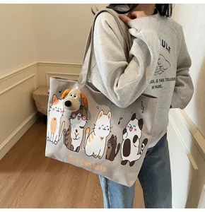 Detailed view of large capacity canvas tote bag with cute cat prints and plush dog pendant.