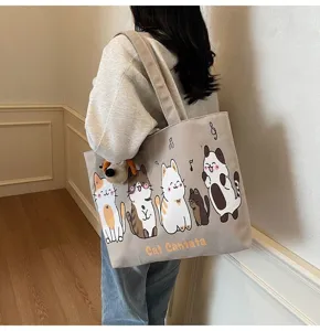 Detail view of canvas tote bag with cute cat print and plush pendant, casual shoulder style.