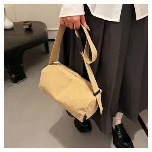 Corduroy cylinder shoulder bag detail showing soft fabric texture and strap adjustment.