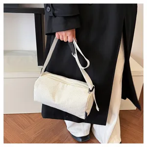 Corduroy cylinder shoulder bag detail view, simple white crossbody bag featuring zipper and adjustable strap.
