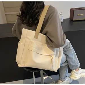Detailed view of the beige canvas tote bag showing wide strap and large capacity design.
