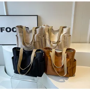 Close-up of multi-pocket canvas tote bags in various colors with sturdy dual straps for daily use.
