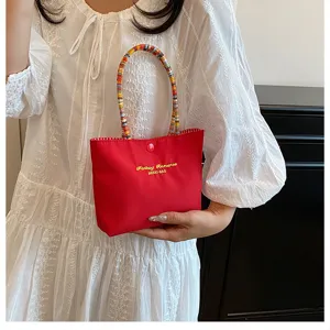 Sac à main rouge en détail, poignée perlée colorée, lettres brodées, joli sac pour téléphone.