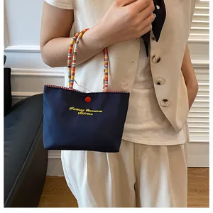 Vue de détail d'un mini sac à main bleu foncé avec poignées perlées colorées et broderie.