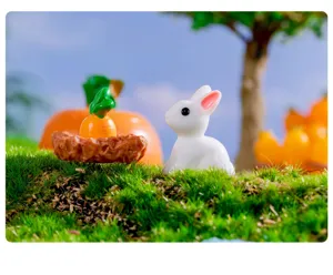 Dettaglio di un grazioso coniglietto bianco in resina e carota per decorazione di micro paesaggio.