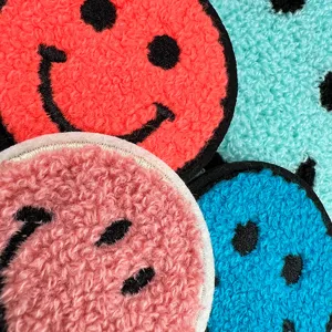 Close-up detail of colorful smiley face tufted embroidery patches with soft textured fluffy fabric.
