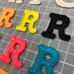 Detailed view of colorful embroidered letter R patches, fine stitching texture for DIY decor.