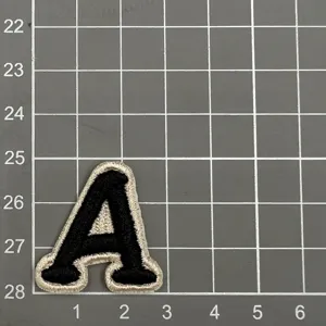 Nahaufnahme Detail des schwarz-weißen gestickten Buchstaben A Aufnähers auf Matte.