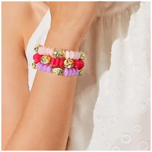 Detalle de pulsera de cuentas multicapa con cuentas rosas, rojas, moradas y acentos dorados.