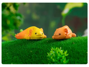 Primo piano di simpatiche statuine di axolotl su erba verde per decorazione di micro paesaggi.