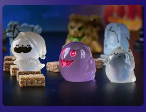 Close-up detail of cute translucent resin ghost miniatures for Halloween micro landscape decor.