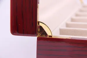 Λεπτομέρεια πολυτελούς ξύλινης θήκης ρολογιών με χρυσό μεντεσέ και απαλή επένδυση.