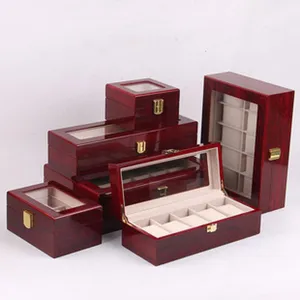 Wooden watch box detail showing multiple sizes and slots with glass lid and beige velvet interior.