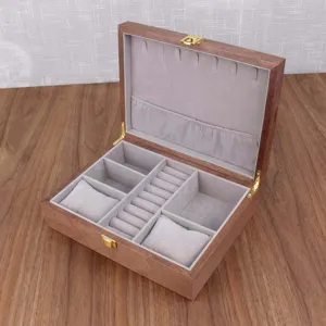 Close-up detail of the wooden jewelry watch box interior, showing grey velvet ring slots and pillows.
