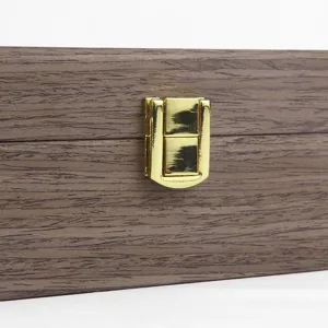 Close-up detail of wooden watch box gold metal clasp and walnut wood grain surface
