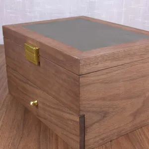 Wooden storage box detail showing walnut finish texture and gold metal clasp hardware.
