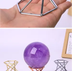 Detailed shot of metal geometric display stand and purple crystal ball in home decor setup.