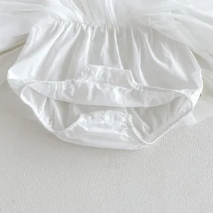 Detail shot of infant baby girl white tutu romper bodysuit, showing snap closure and soft cotton fabric.