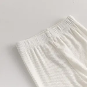 Close-up view of infant white ribbed leggings, soft and stretchy fabric detail for babies.
