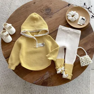 Infant knit hoodie and leggings set detail, yellow and white baby clothing flat lay.