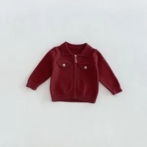 Close-up detail of infant dark red knit cardigan with lapel, zipper, and chest pockets.