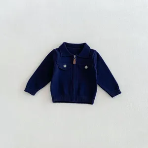 Close-up detail of infant knitted cardigan showing lapel collar, front zipper, and pockets.
