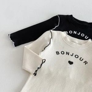 Dettaglio t-shirt neonato a maniche lunghe a costine, bordo ondulato con stampa.