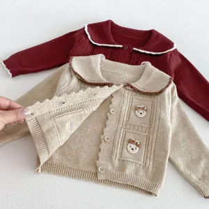 Close-up detail of infant knitted cardigan with cute bear applique, lapel and single-breasted buttons.