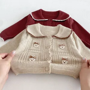 Detailed view of infant knitted cardigan featuring cute bear embroidery and single buttons.