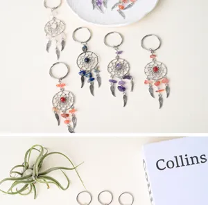 Detailed view of natural crystal chip dreamcatcher keychain with metal wing charms.
