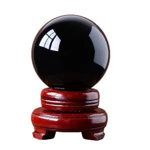 Black obsidian crystal ball ornament with wooden base for home office feng shui decor.